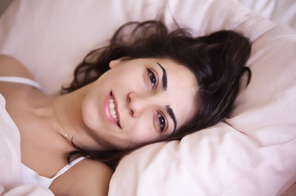 Gesunder Schlaf Das Foto zeigt eine lächelnde Frau im Bett.