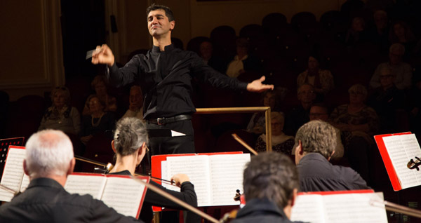 Das Foto zeigt einen Dirigenten von einem Streichorchester.